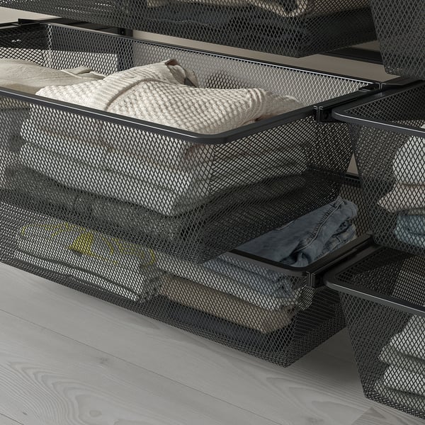 Mesh baskets in drawers hold folded clothes, allowing air circulation. Part of a modular wall-mounted storage system.