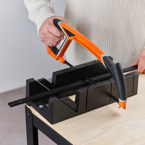 Person using orange tool on black mounting rail, aligning wall uprights straight.