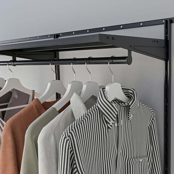 Black metal closet rail with clothes. Includes striped shirt, hangers, and shelf.