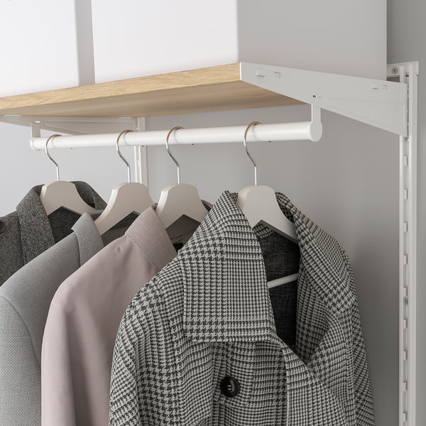 A closet system with clothes hangers and shelves. Textiles hang from a white rod below light wood shelves mounted on a white frame.