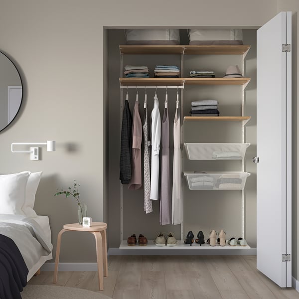 White BOAXEL closet in bedroom, with shelves, hanging rods, and baskets.