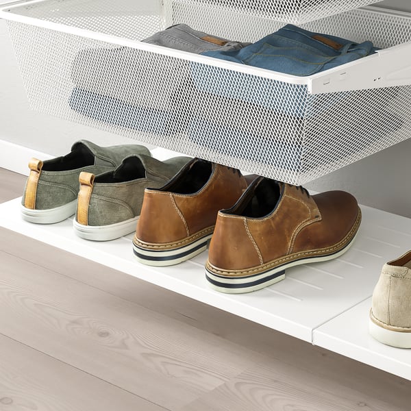 White mesh shelf holds folded jeans, green trainers, and brown dress shoes neatly on a white shelf under a wall-mounted mesh drawer.
