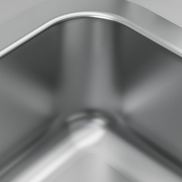 Stainless steel sink close-up. Smooth, shiny, reflective surface. Curved edges, sleek design.