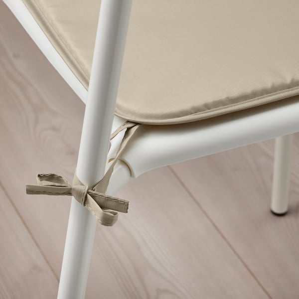Beige BRÄMÖN chair pad secured to white legs. Two-sided, water-repellent fabric for indoor & outdoor.
