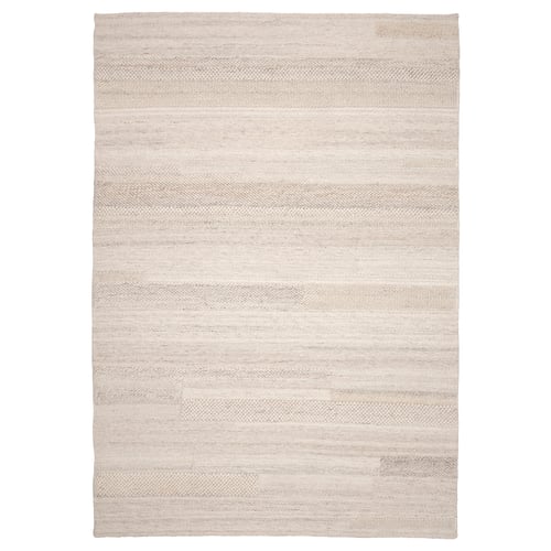 Neutral-toned BRÖNDEN rug with woven textures, handmade from wool and cotton, rectangular shape.