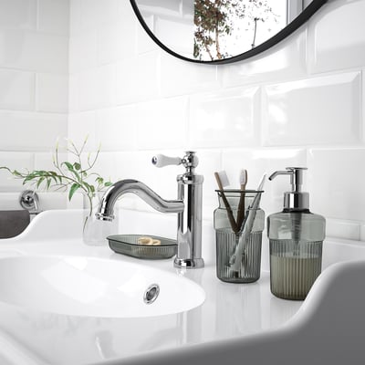 Modern bathroom sink with chrome tap, green soap dispenser, and tray. Minimalist design.
