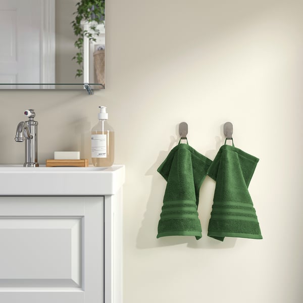 Green BROKGLIM organic cotton towels hang beside white sink with soap dispenser.