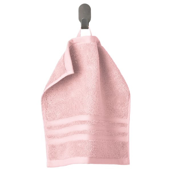 A light pink organic cotton towel hangs on a wall hook. Soft, absorbent with a woven border.