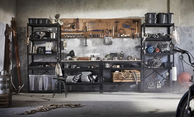 Garage with BROR black metal shelves, tools, and items. Concrete walls,ievy floor, natural light.