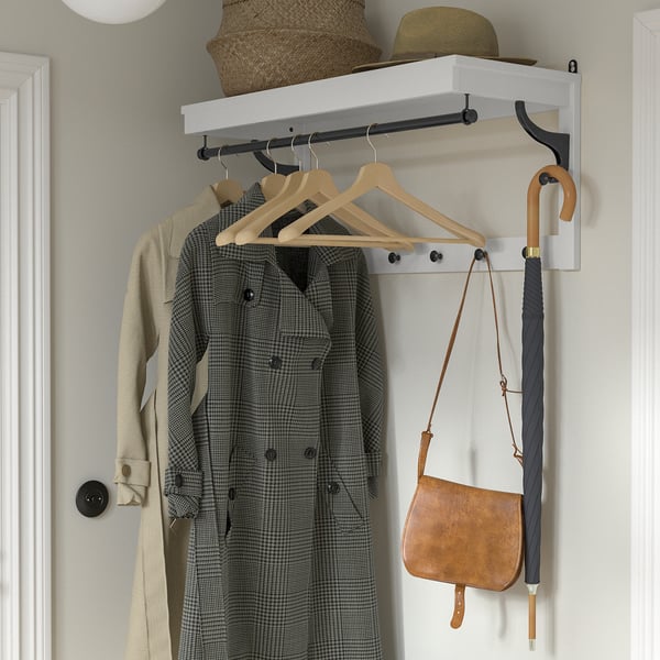 Organised entryway setup featuring BUMERANG coat hanger with hanging jackets, hat, basket, purse, and umbrella.