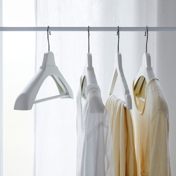 White hangers and clothes on rack; shoulder shaper protects sweater shape.