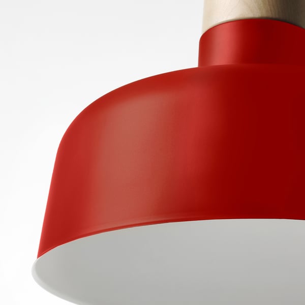 Close-up of modern red pendant lamp, smooth finish. Shade curves gently, top with wood detail. High-quality, bright interior visible.