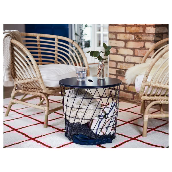 BUSKBO armchairs, natural rattan, circular coffee table with storage, red & white rug, eucalyptus plant, brick wall background.