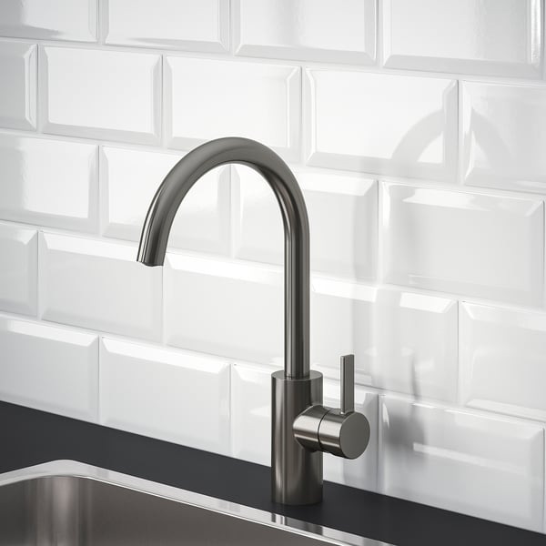 Modern kitchen tap with high arch, pewter finish, set against white tiled backsplash.