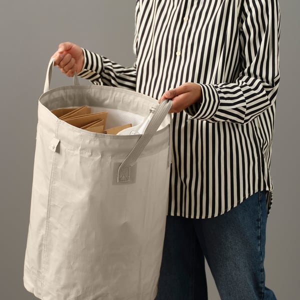 Person holding a DIMPA sorting bag with handle, filled with items. The bag has a divider inside.