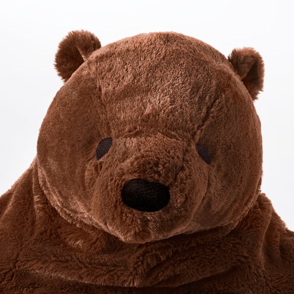 Large plush brown bear with soft fur, black eyes, and nose; inviting, plush, and comforting.