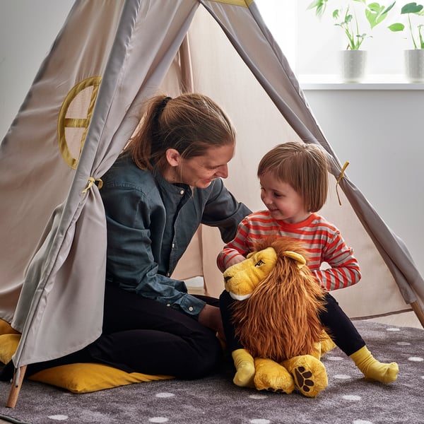 Person, child & stuffed lion in tent.