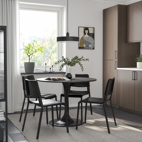 Modern dining area with black round table, chairs, and large window.