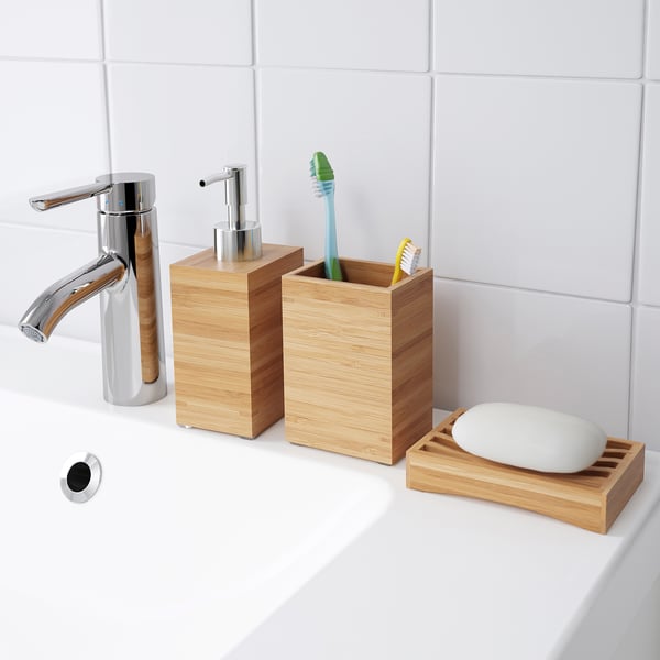 A modern bathroom sink with a chrome tap, wooden soap dispenser, toothbrush holder, and soap dish.