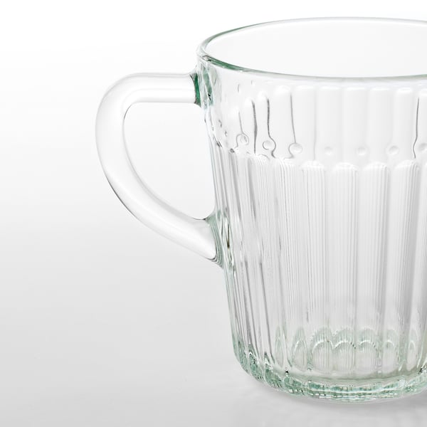 Clear glass mug with a sturdy handle, showcasing vertical ribbing for grip, standing on a plain surface.