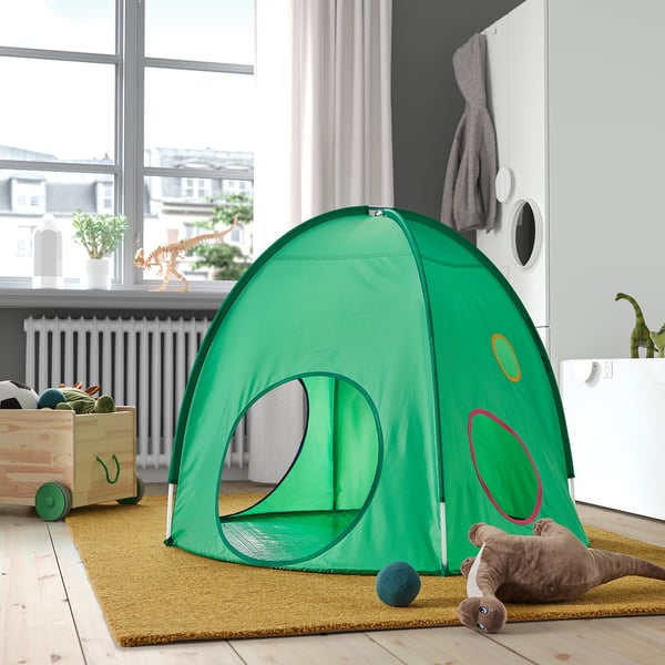 Small green kids play tent, bright and airy, placed indoors on a rug, with a dog toy nearby.