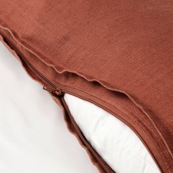 Close-up of rust-colored cushion covers zip, revealing white inner cushion, illustrating removable design.
