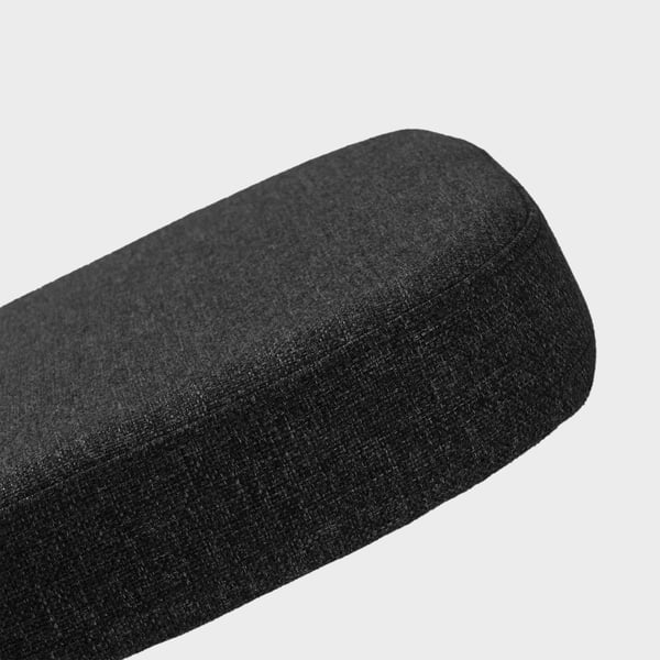 Black fabric-covered cylindrical pillow on white background. Soft, textured surface indicates comfort and support.