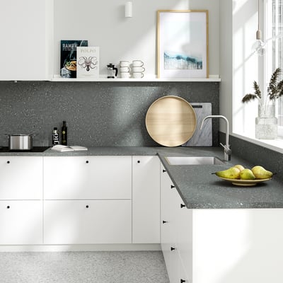 Modern kitchen with grey countertop, wooden tray, fruits, stylish tap, books, mugs, and plant.