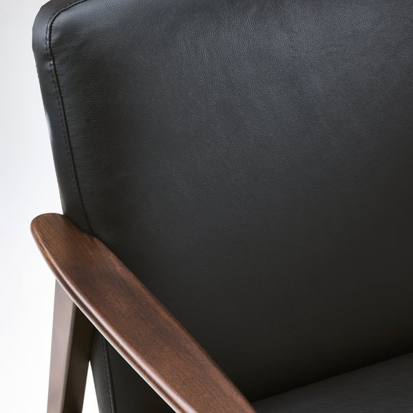 Close-up of modern chairs dark brown wood armrest and black upholstered seatback, showcasing sleek design and sturdy craftsmanship.