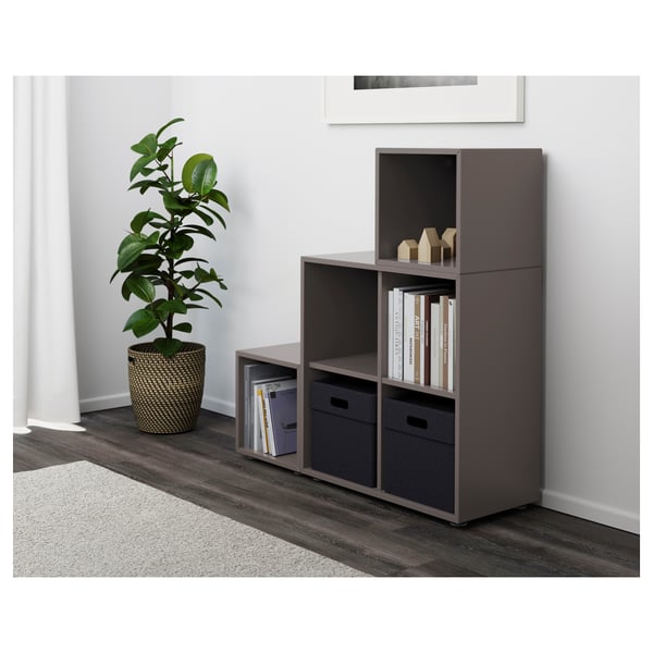Modern grey storage unit with open shelves, closed cabinets, and two fabric drawers, holding books and plant.