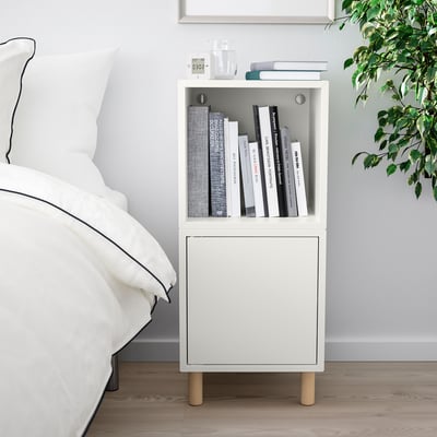 Modern bedroom with white bedside table beside bed, holding books, alarm & plant. Character count: 44