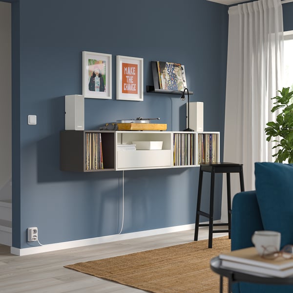 Modern room with blue walls, EKET unit, blue chair, records, books, speaker, plant, rug.