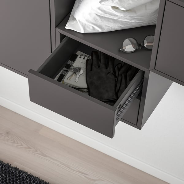 Open black drawer near bed, holding wallet, gloves, and keys; shows hidden storage.