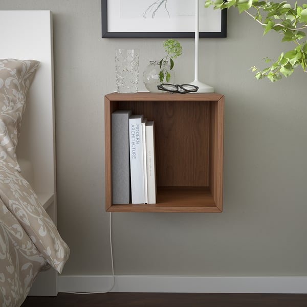 Brown wooden wall cabinet with books & decor in bedroom.