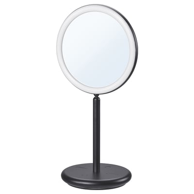 An EKFÄNN two-sided table mirror. Its black, circular with a pinched middle, and integrated lighting. The design includes a stand with a base.