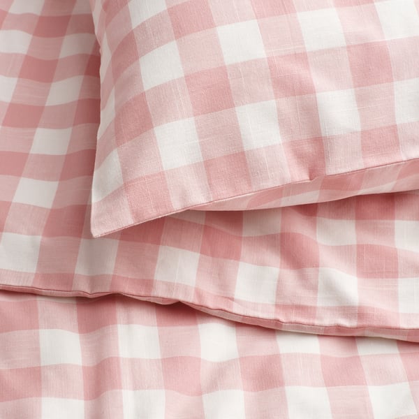 Stack of pink and white gingham check duvet covers, neatly folded, showcasing high-quality, soft cotton texture.