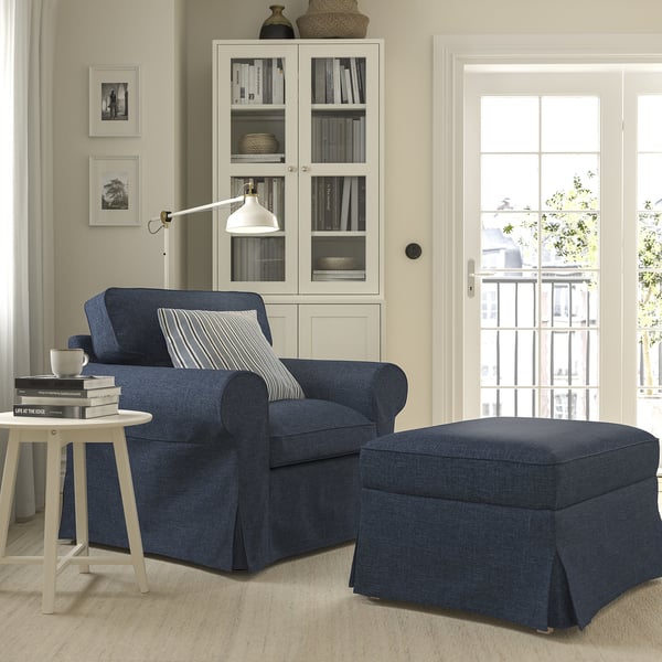 EKTORP navy blue armchair & ottoman, cosy & oversized, with white side table & glass bookshelf.