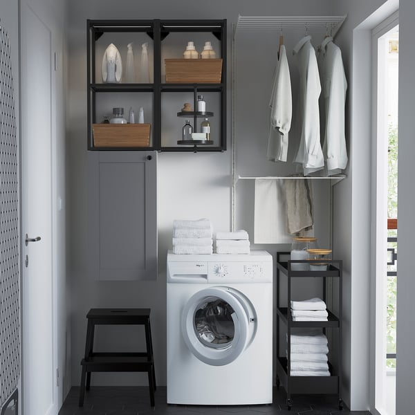 Grey laundry setup with ENHET furnishings: wall cabinet, washing machine, step stool, hanging rail, and shelves.