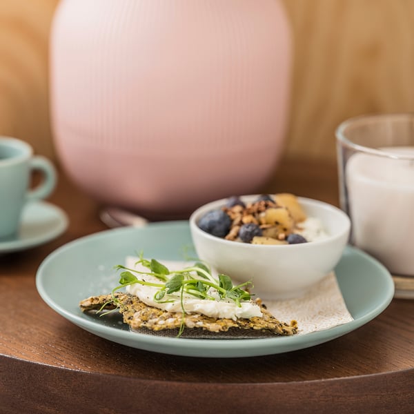 Blue plate with green food, white bowl with yoghurt and berries, on wooden table.