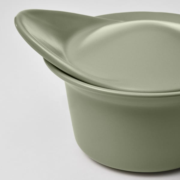 A close-up of a green stoneware dish with a smooth lid and rounded handle, showcasing its sleek, durable finish.