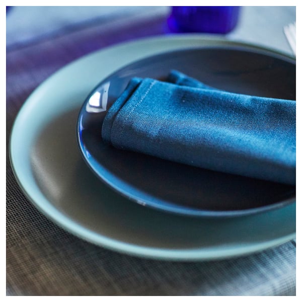 Blue glazed stoneware plate with napkin. Simple, round design. Table setting ready.