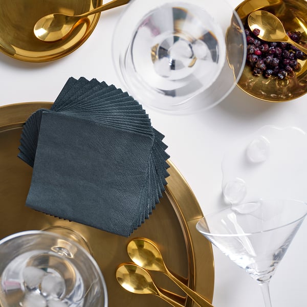 Golden dishes, napkins, and glasses with ice on white table. Napkins centered, larger than glasses.