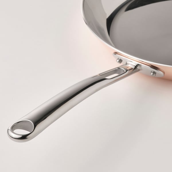 Close-up of high-quality FINMAT frying pan handle, showcasing sleek, polished stainless steel, reflecting durability and elegant design.