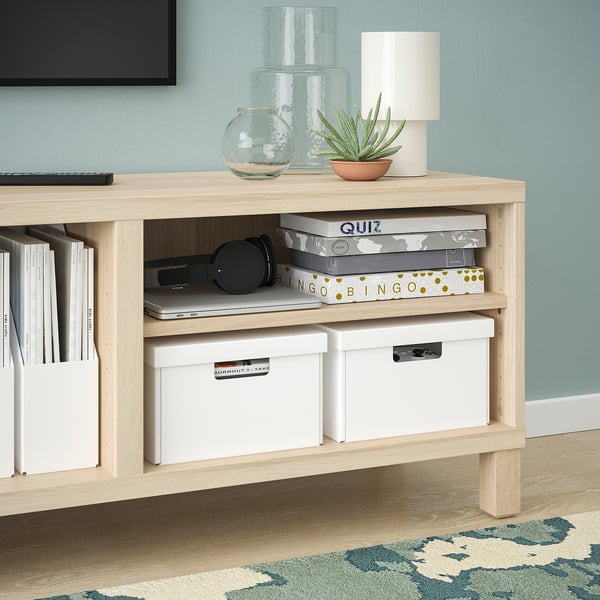 Light wood shelf with storage boxes, headphones, and a laptop.