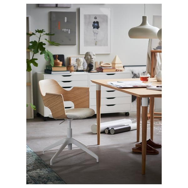 Modern light wood and white office chair beside desk. Bright room with decor.