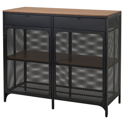 Displays a black FJÄLLBO sideboard with a wooden top. It a metal mesh design and two glass doors, providing a modern industrial look.