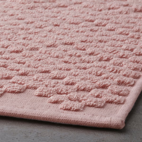 Close-up of soft, textured light pink bath mat, showcasing its absorbant cotton weave.