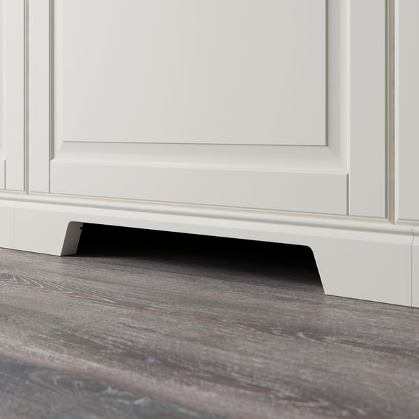 Black plinth with cut-out for ventilation under white cabinet.