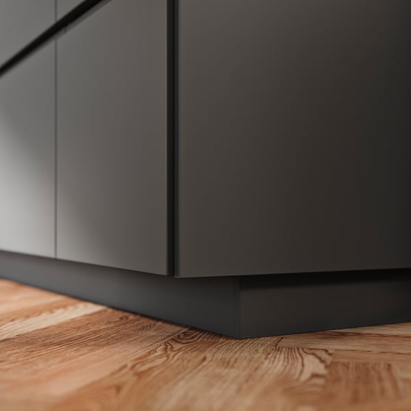 A grey FÖRBÄTTRA kitchen cabinet plinth made of plastic foil and polypropylene, neatly fitted against a wooden floor.