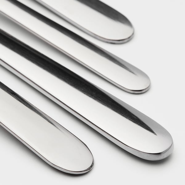 Four polished, stainless steel knives aligned neatly in a row, reflective surfaces showcasing high quality.